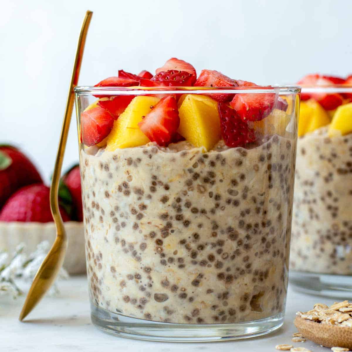 A glass cup filled with overnight oats with water and topped with fresh fruits.