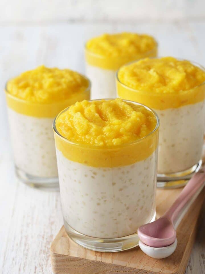 Vegan tapioca pudding in four glasses, topped with a mango puree.
