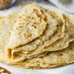 Folded oat tortillas served on a wooden board layered with parchment paper.