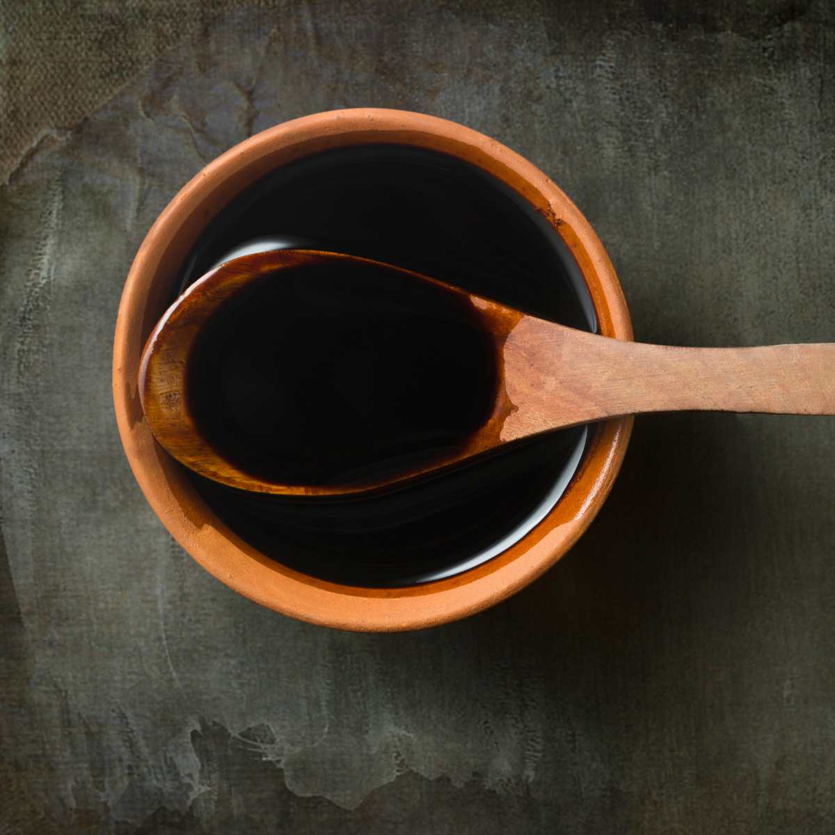 Bowl with tamari sauce and a spoon dipping into it.