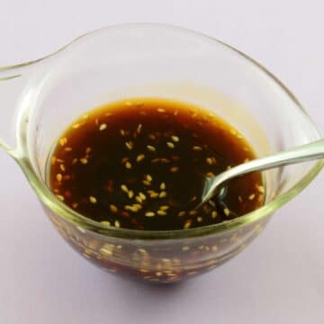 Glass bowl full of homemade soyaki sauce with a spoon.