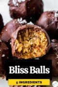 A bliss ball covered with chocolate, with a bite taken out of it and text overlay "Bliss Balls 5 ingredients."