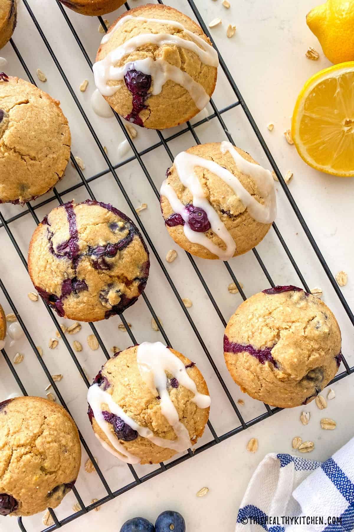 Lemon blueberry muffins on a cooling rack drizzled with a lemon glaze.