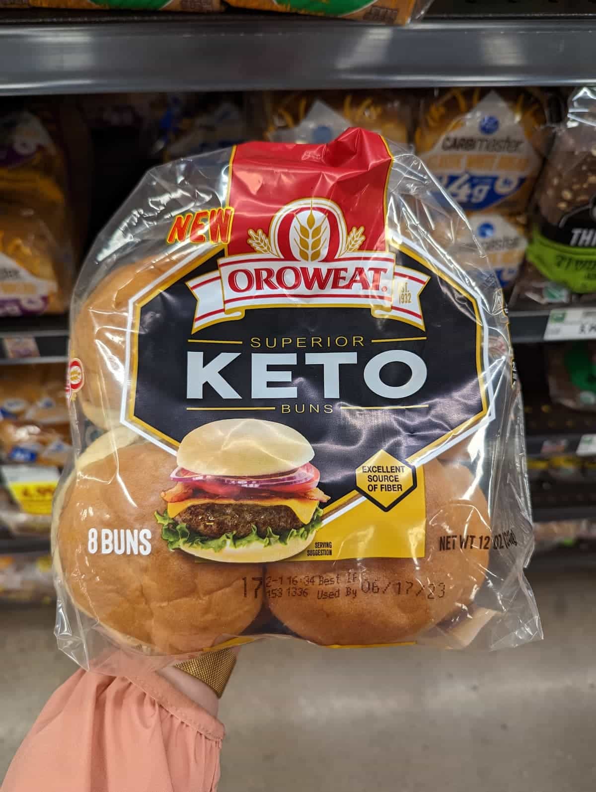 A hand holding up a package of Oroweat Superior Keto Buns.