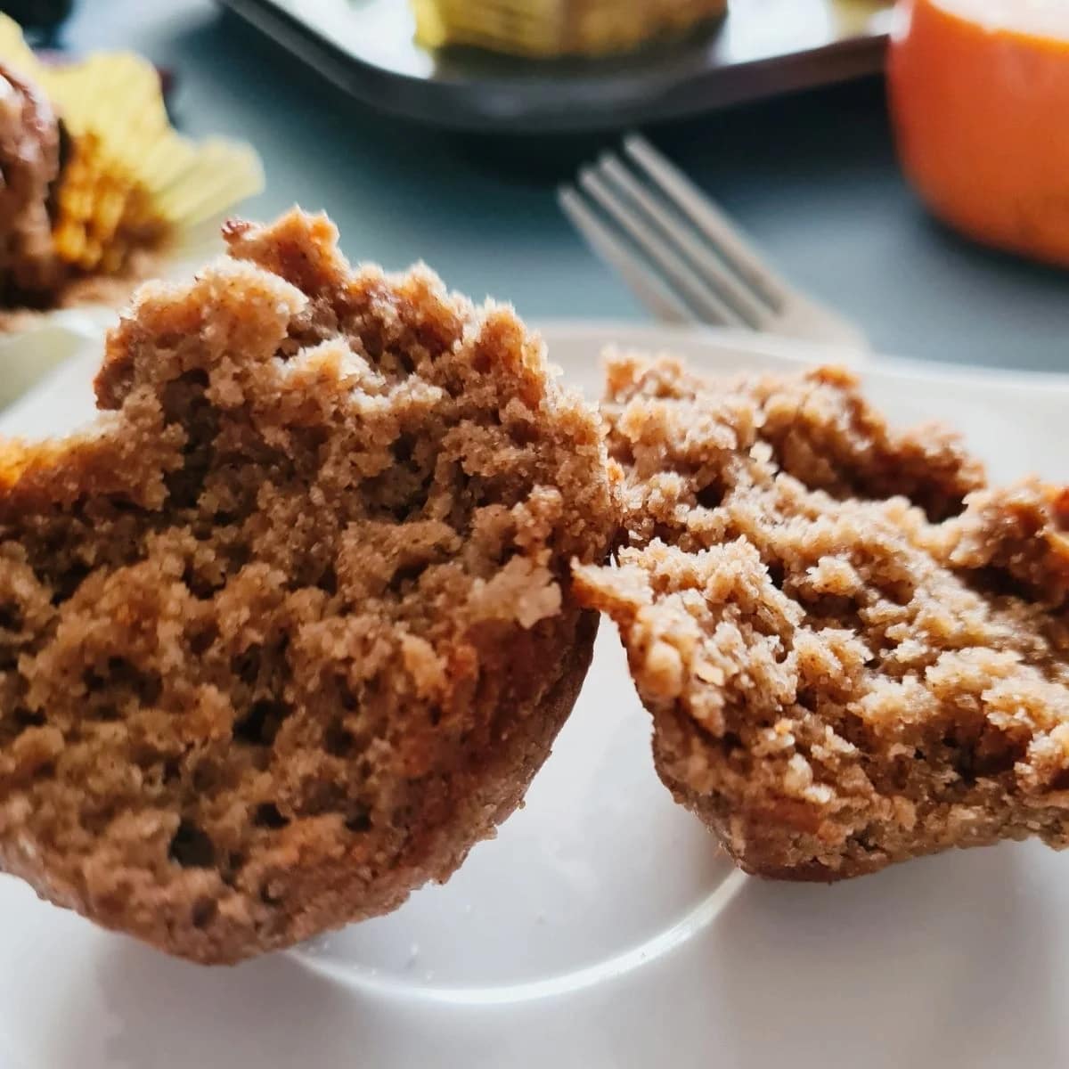 A spiced persimmon muffin on a plate, cut in half.