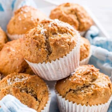 Vegan cinnamon coconut muffins in a pile on top of a cloth napkin.