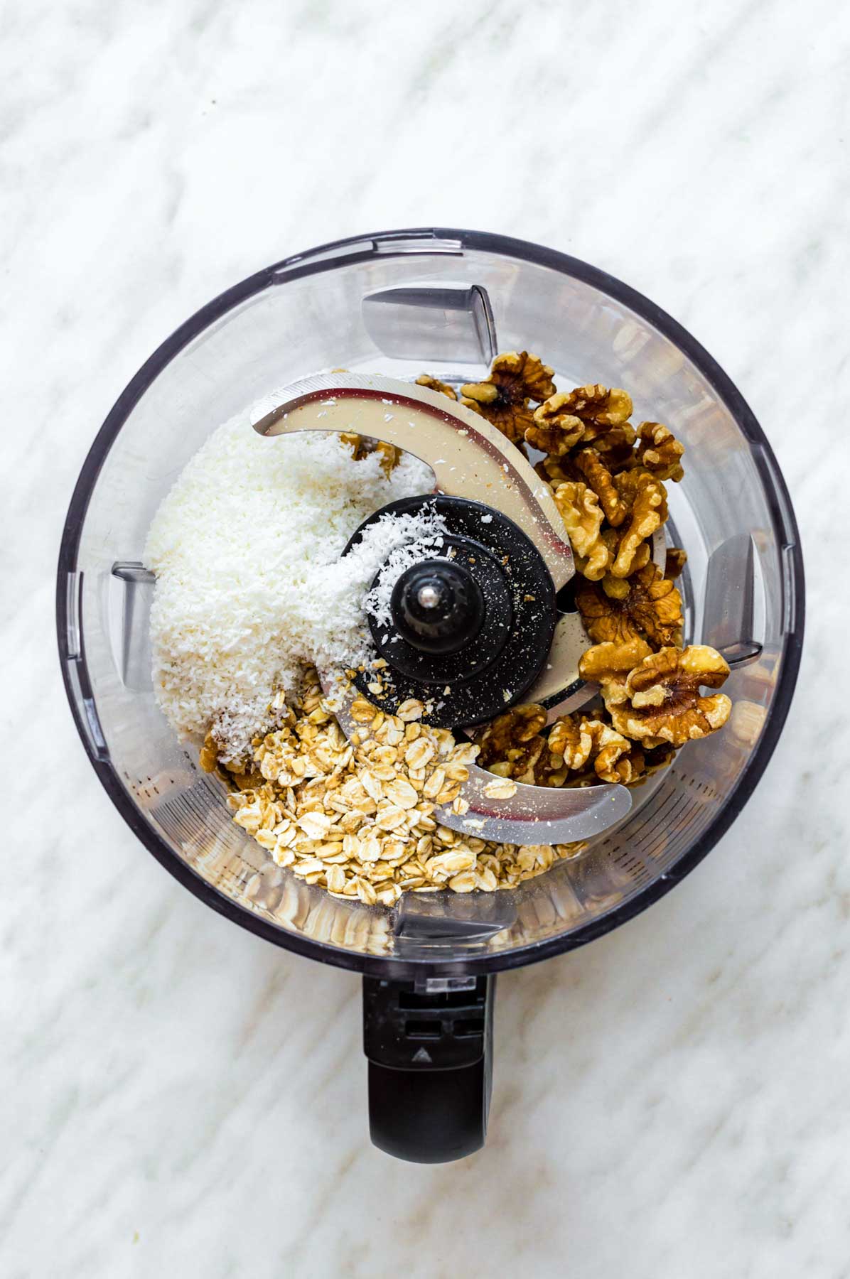 Walnuts, oats, and shredded coconut added to a food processor.