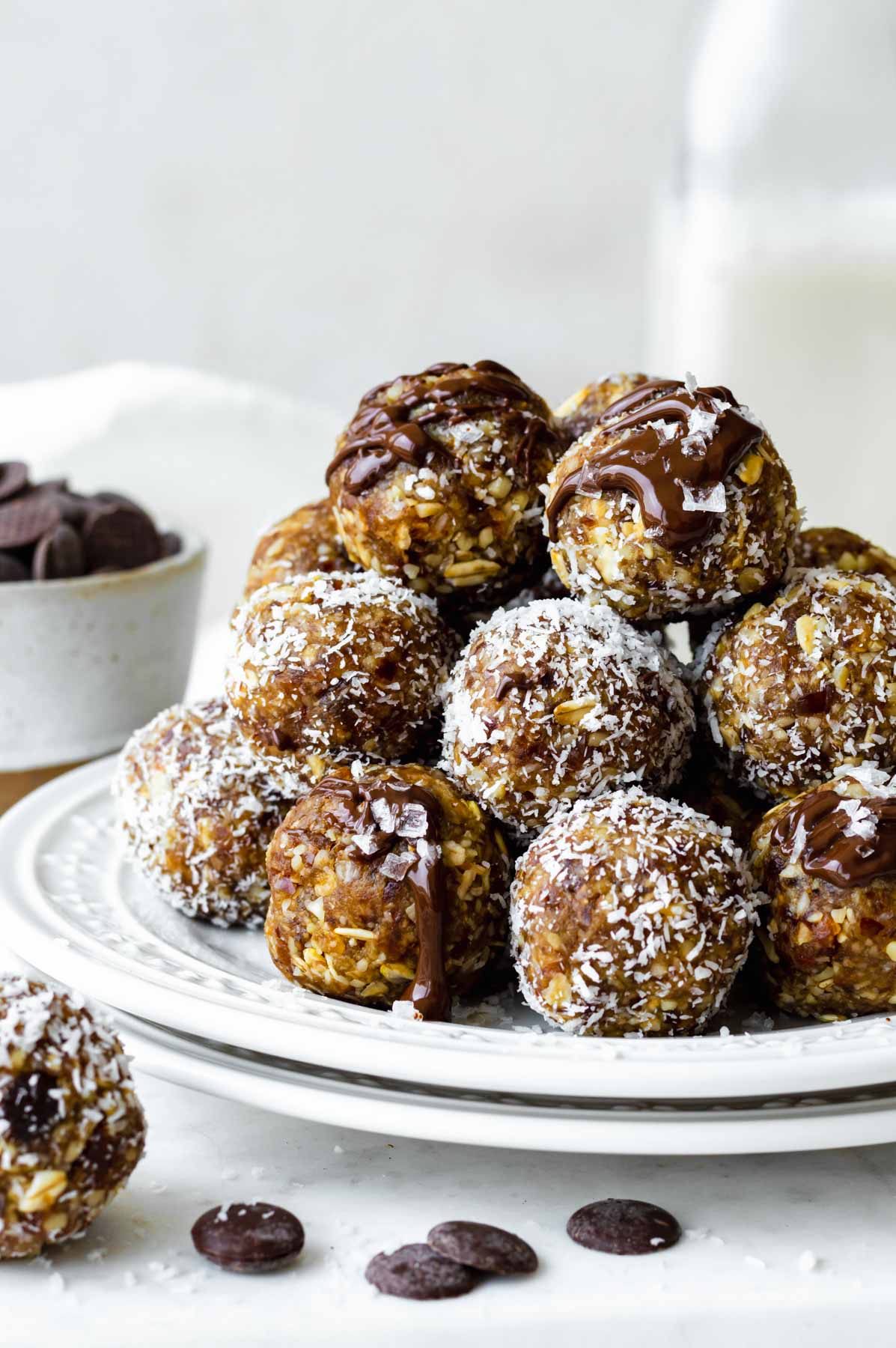 Bliss balls stacked on top of each other topped with melted chocolate and sea salt.