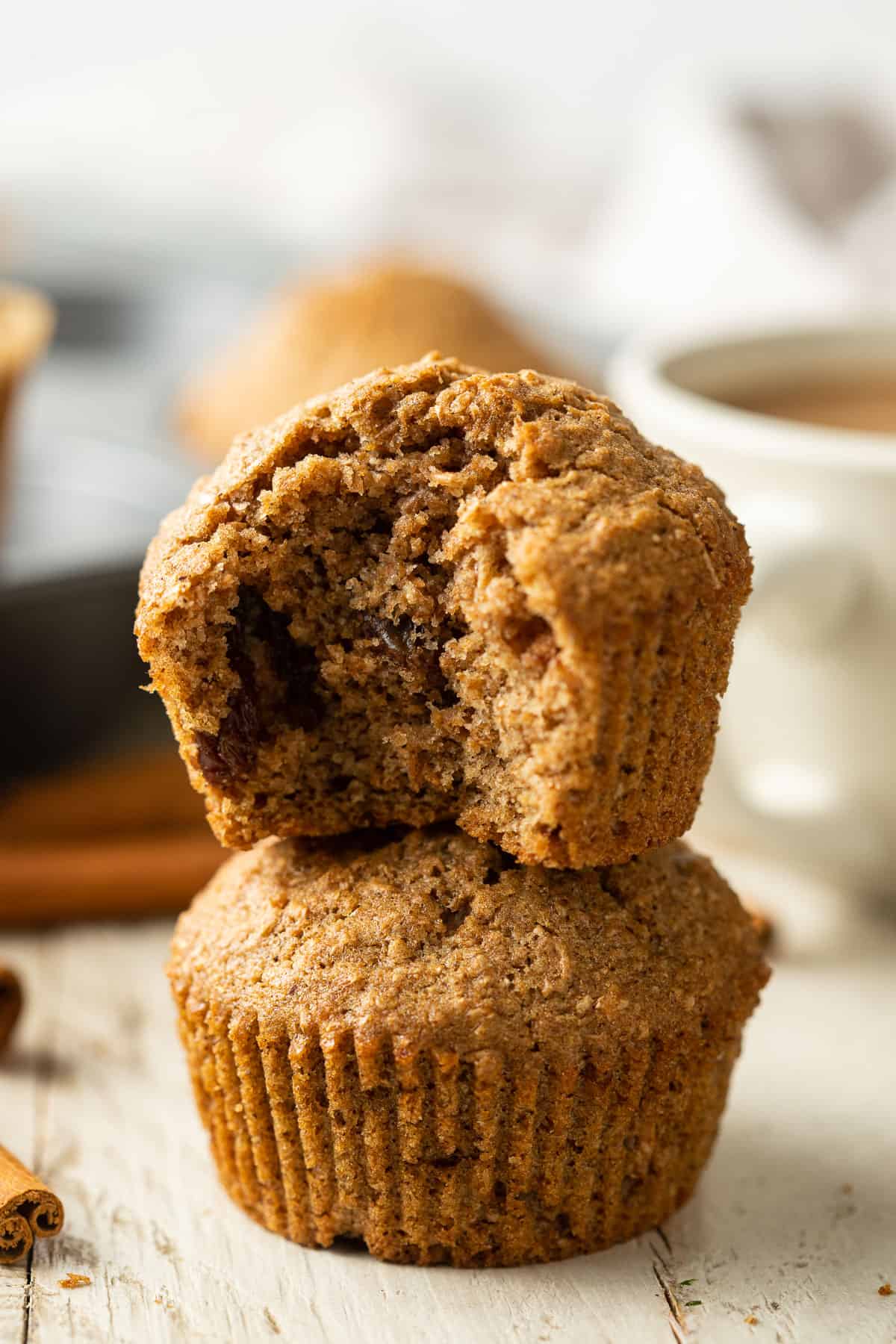 One vegan bran muffin stacked on another with a missing from the top one.