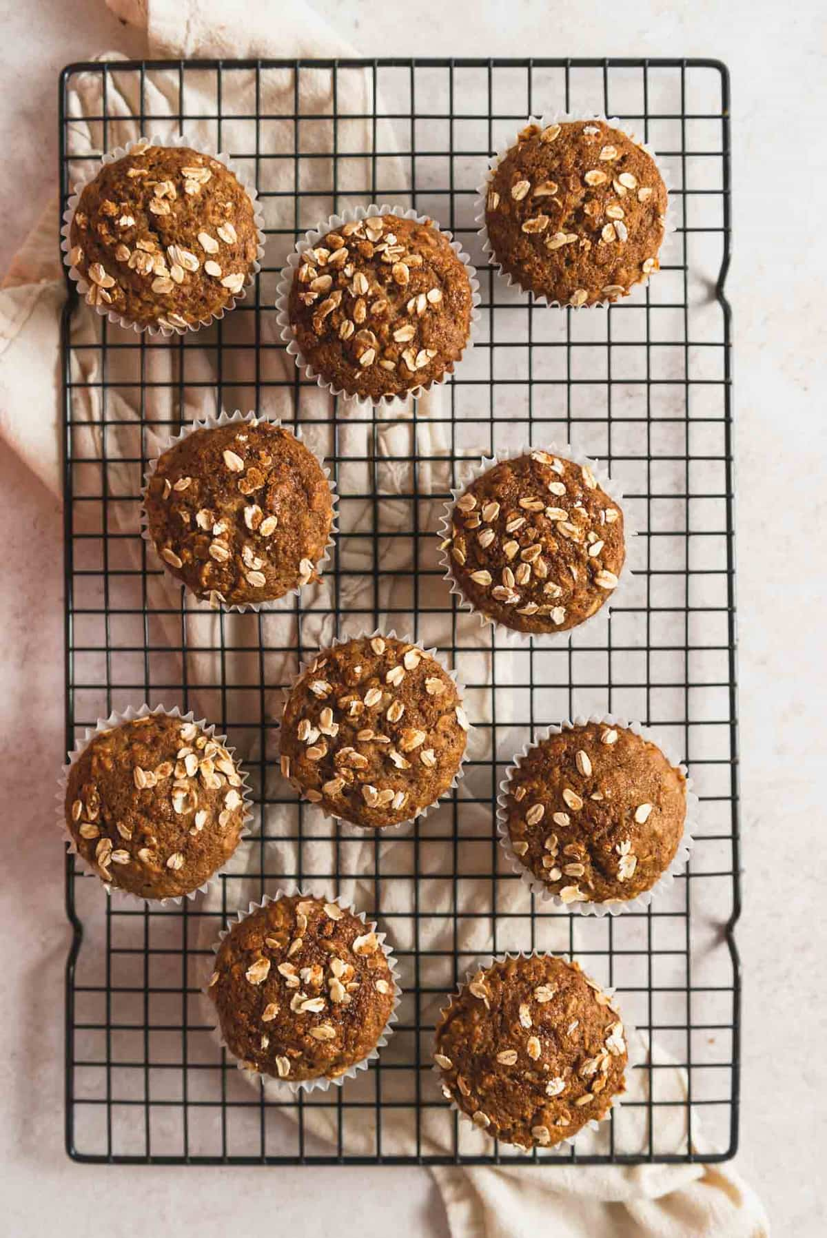 Oatmeal meal muffins on a cooling racked, topped with rolled oats.