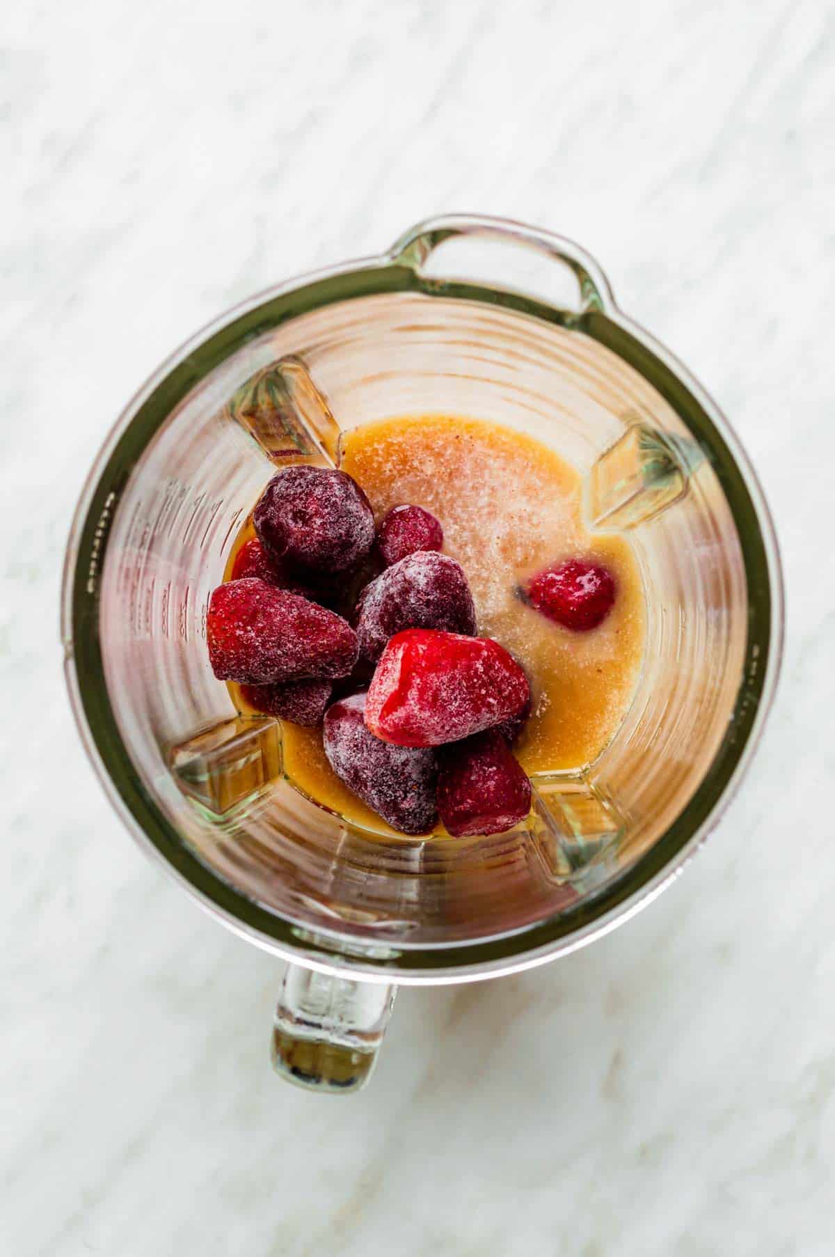 Strawberries, almond milk, and black tea added to a blender.