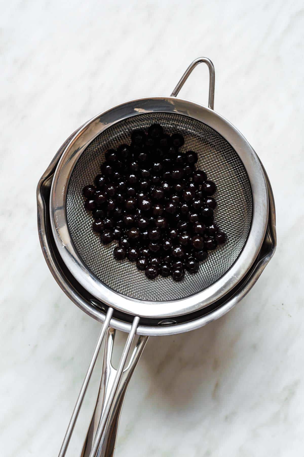 Cooked tapioca pearls draining in a colander.