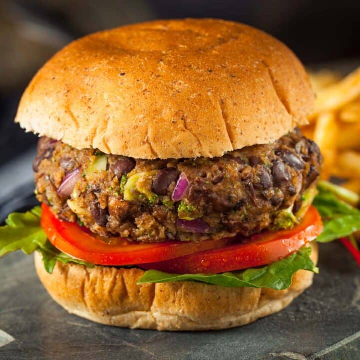 Veggie burger on a vegan burger bun with lettuce and tomato slices.