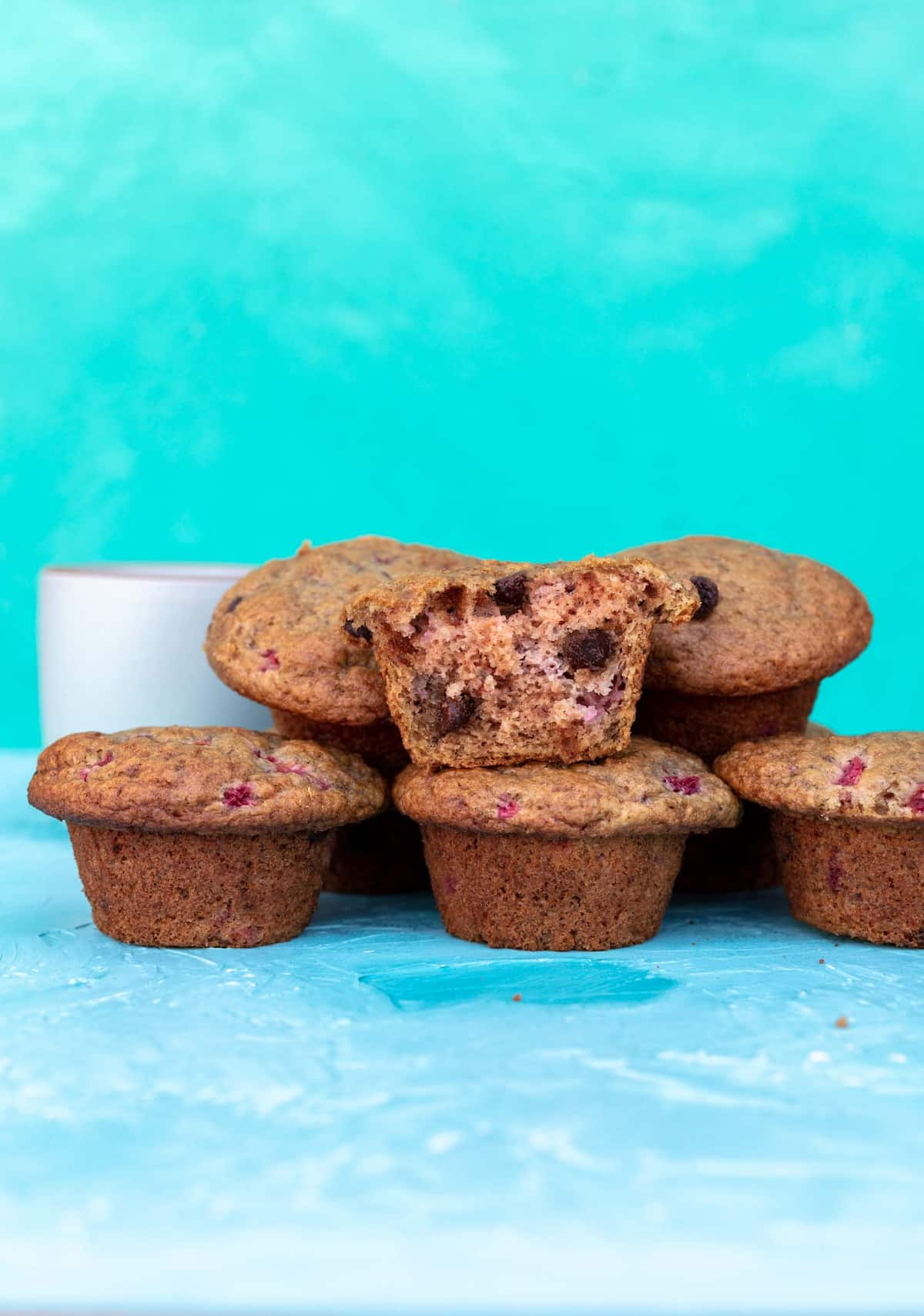 Plum muffins in a pyramid with one cut in half showing the inside.