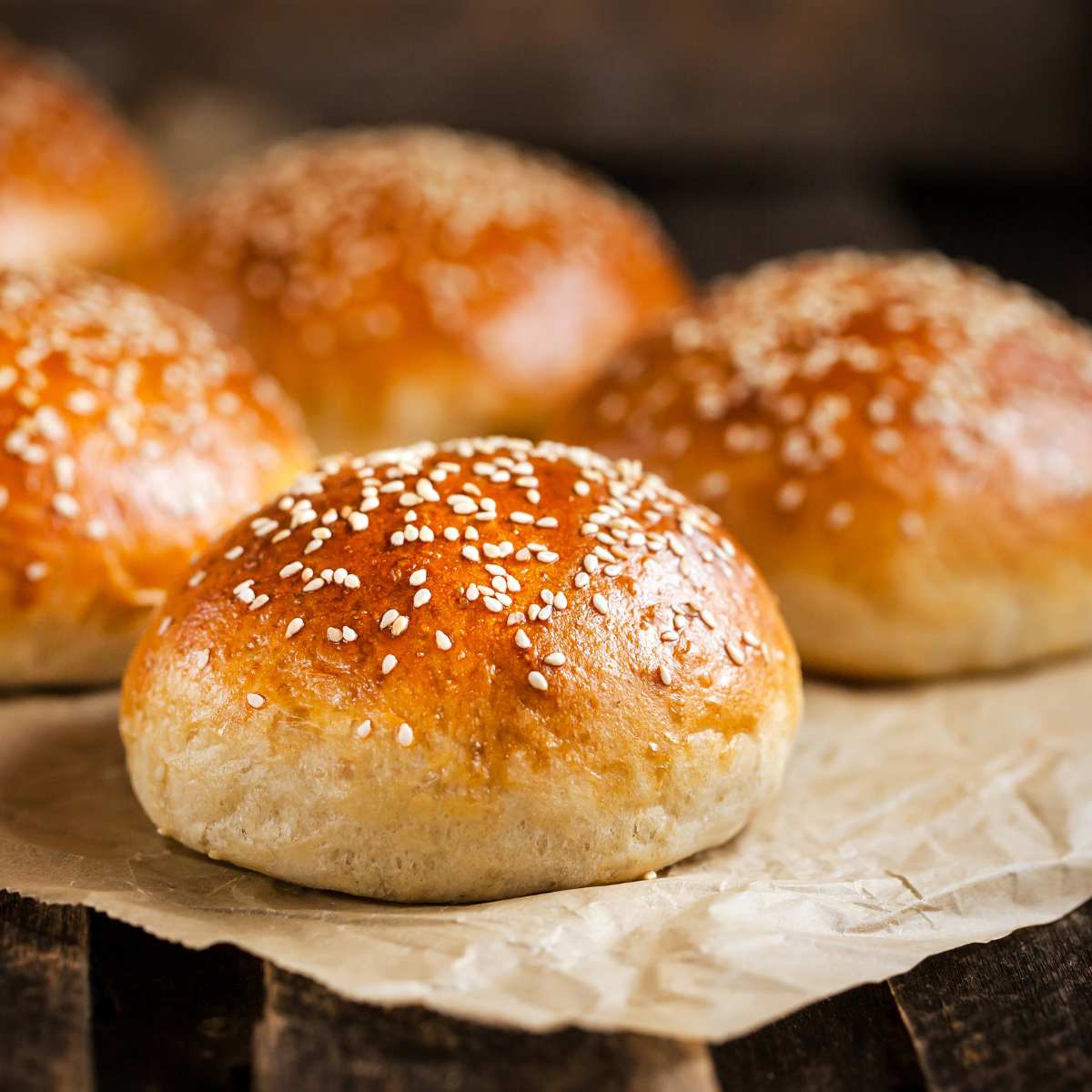 Freshly baked vegan burger buns with sesame seeds on top.