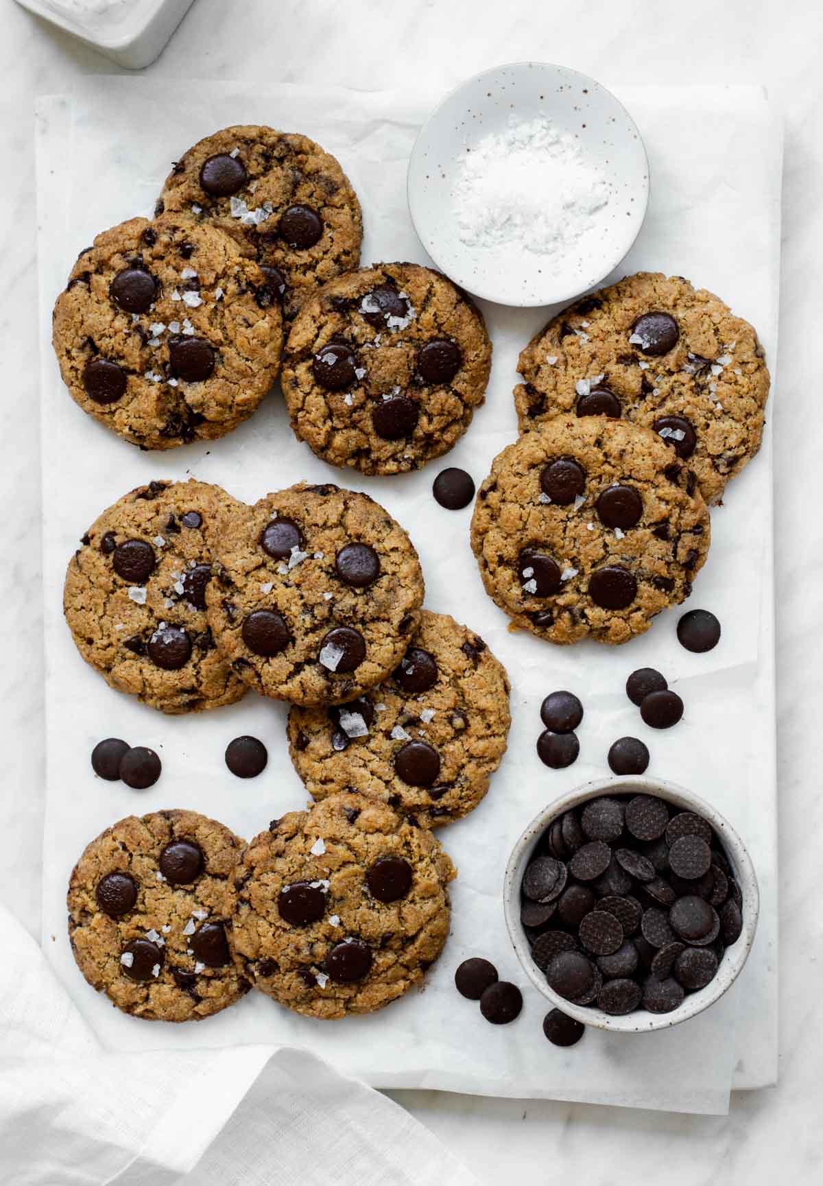 Oat flour cookies sprinkled with sea salt, and placed on a marble board layered with parchment paper.