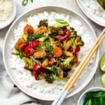 Pad pak served in a white plate over a bed of steamed rice.