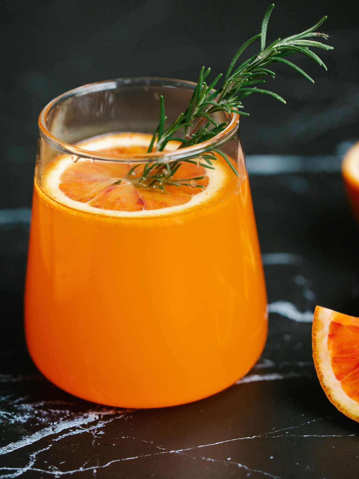 A dried orange slice floating in a glass of juice as garnish.