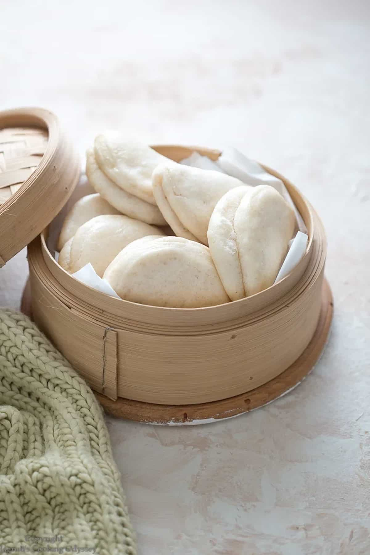 Steamed bao buns in a bambo steamer basket.