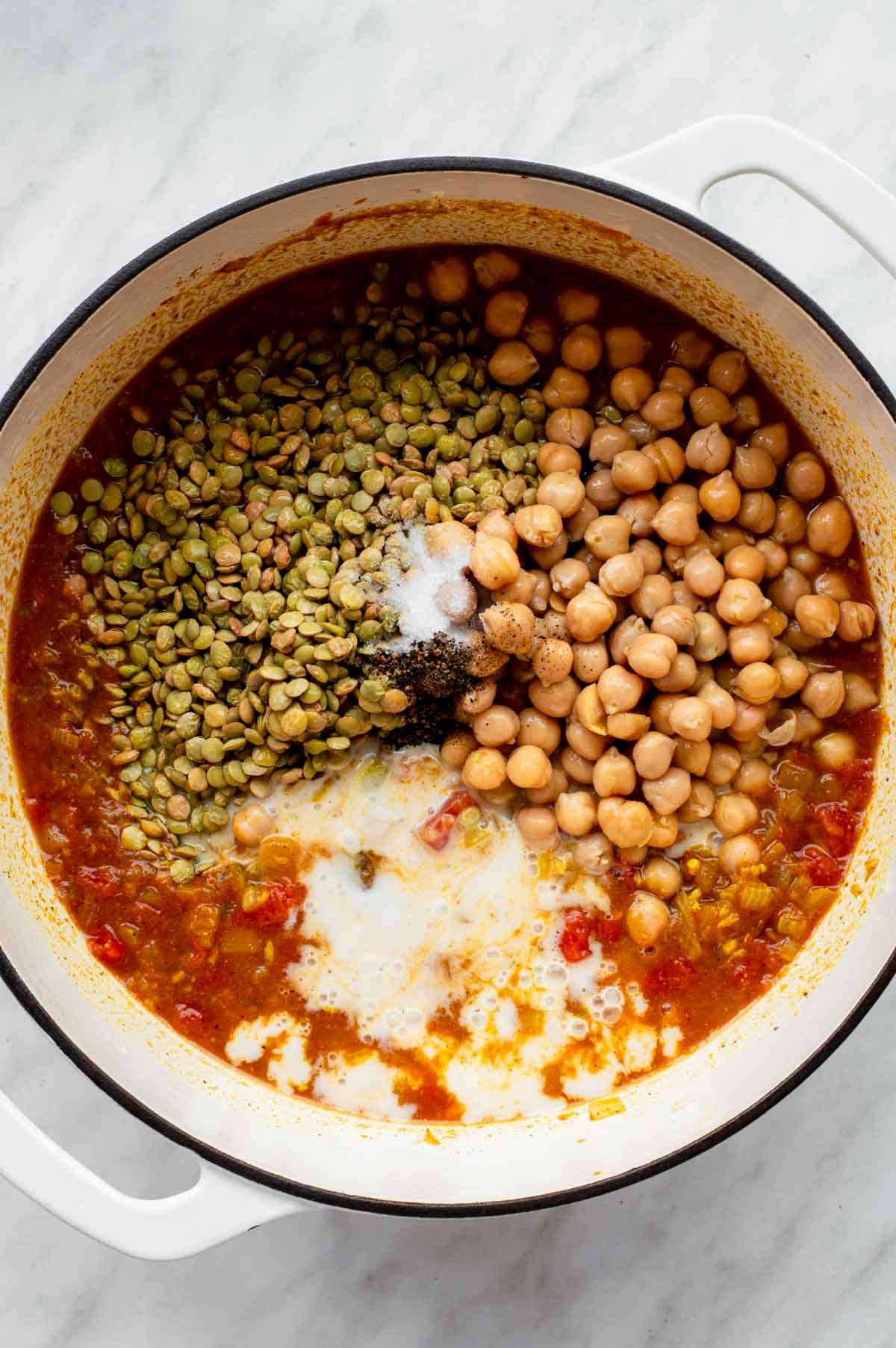 Curry ingredients added to a white Dutch oven.