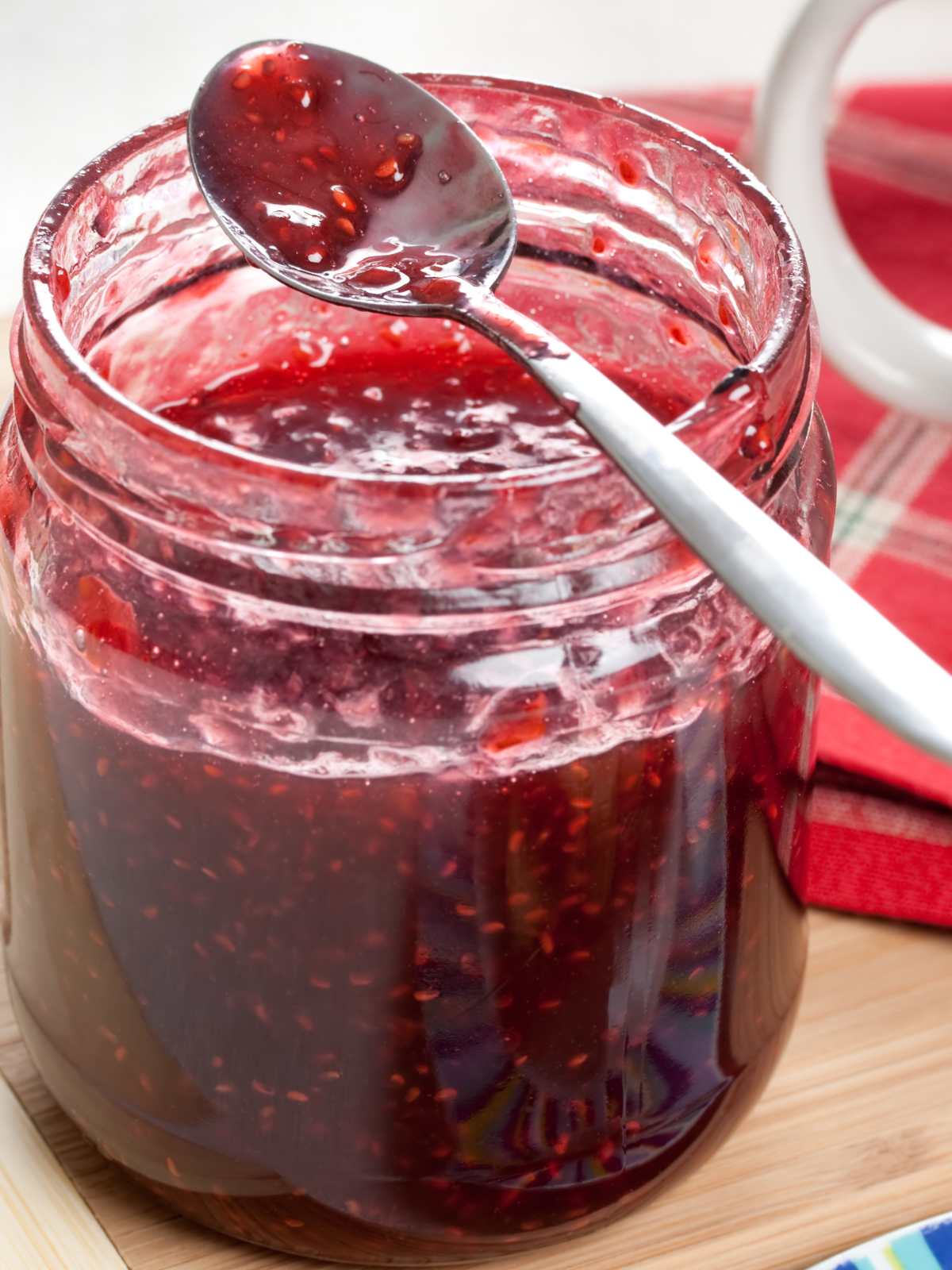 A jar of raspberry jam with a spoon resting on top.