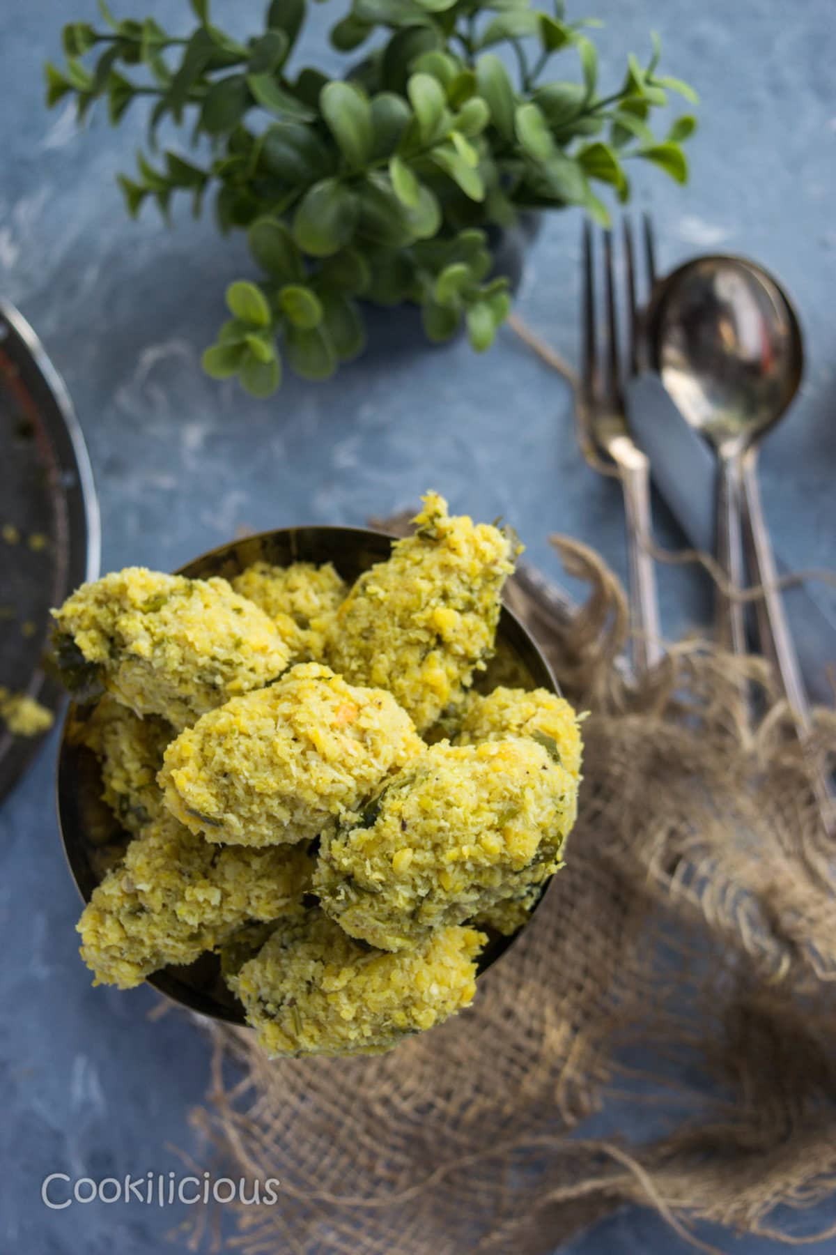 A platter of steamed lentil balls next to cutlery.