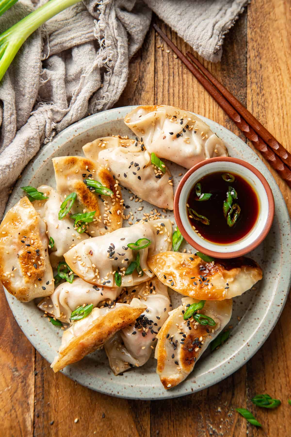 Steamed vegan potstickers on a plate, served with dipping sauce.