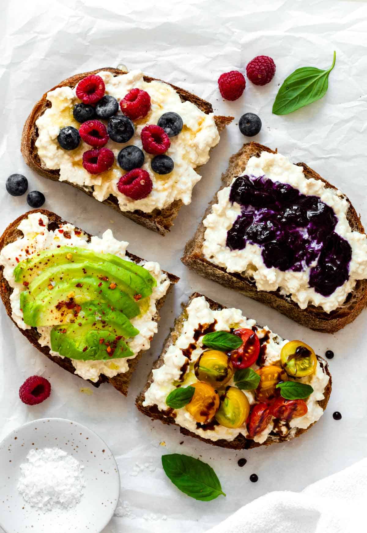 Four cottage cheese toasts with different toppings on them - two savory and two sweet.