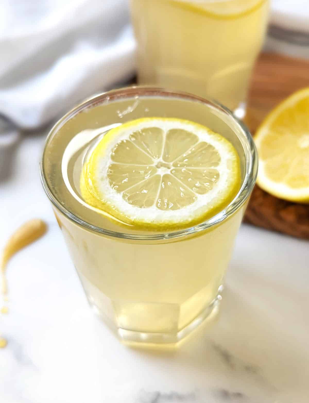 Apple cider vinegar and lemon juice in a glass, topped with a slice of lemon.