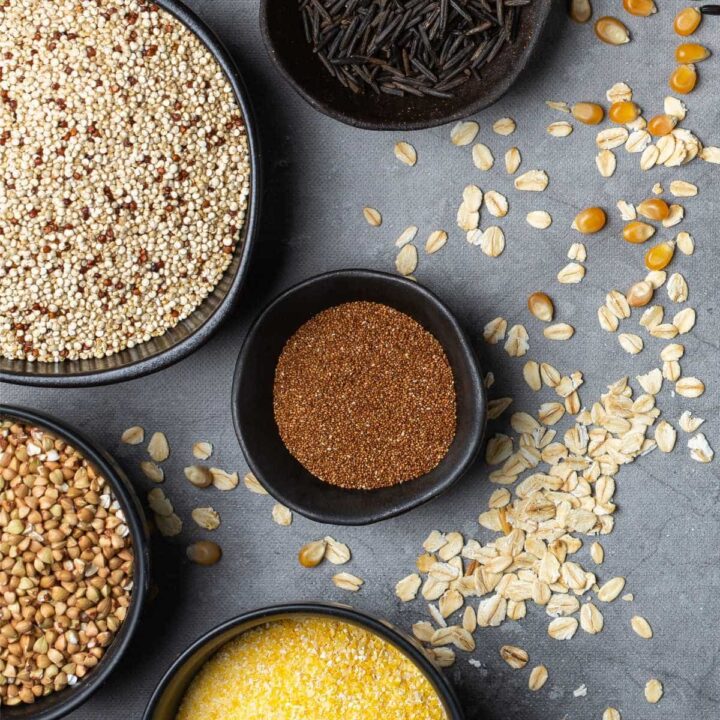 Various whole grains in bowls that are used as barley substitutes.