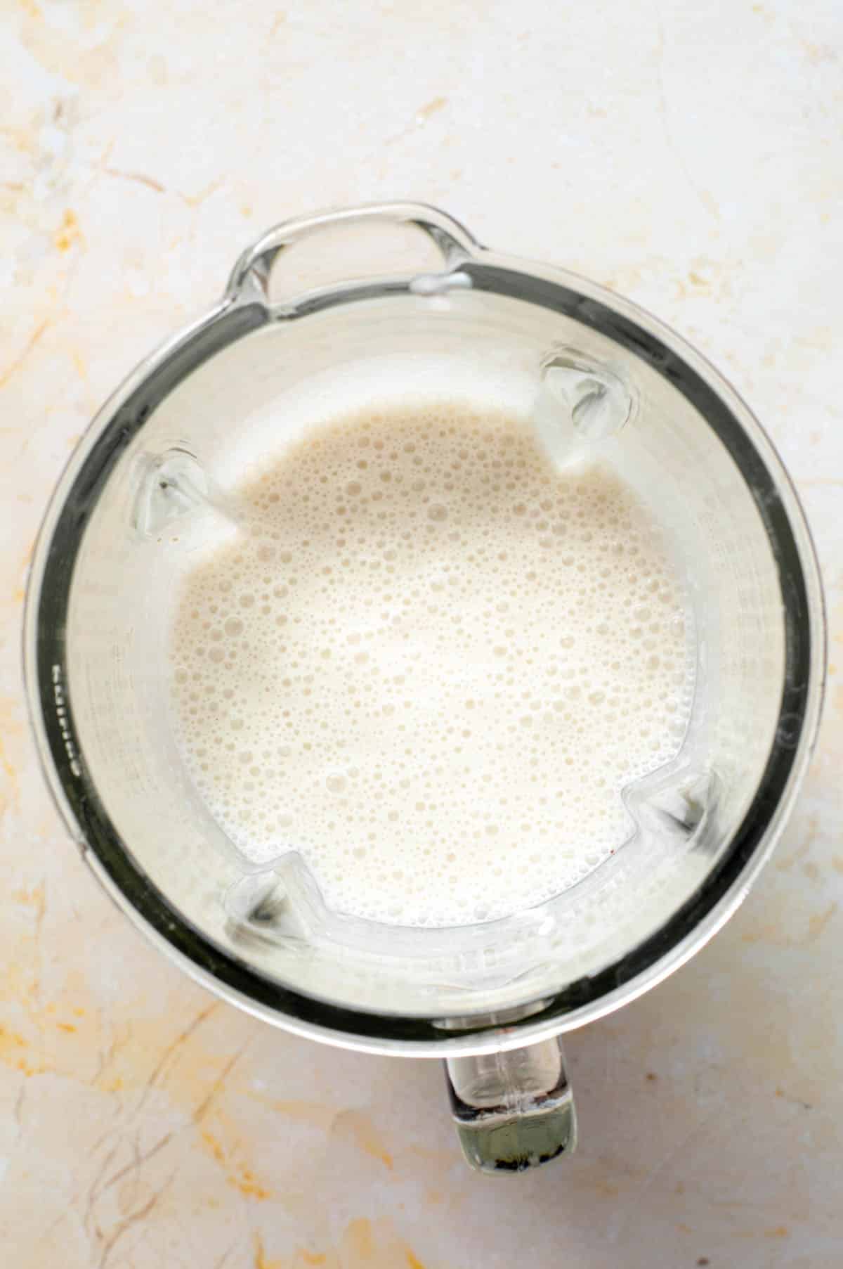 The blended up coconut shake in a blender pitcher.