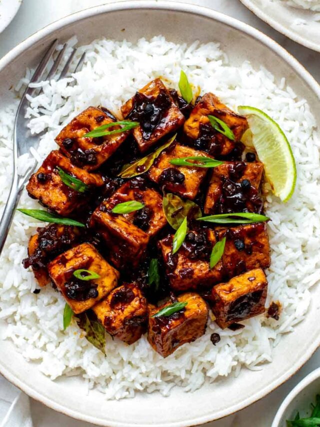 Tofu adobo served over a bed of rice and topped with sliced green onion.