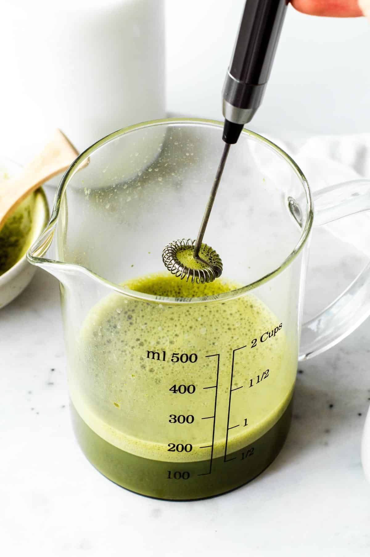 Mixing matcha with an electric milk frother.