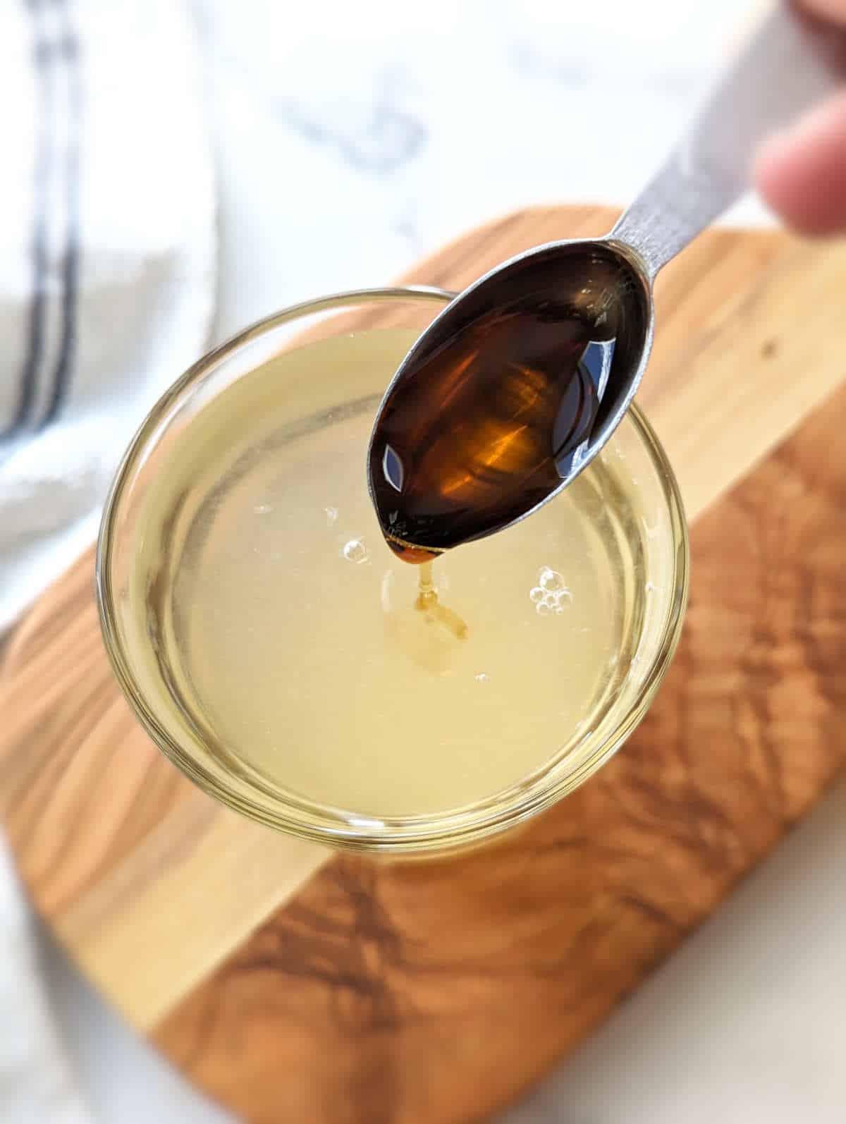 Adding maple syrup syrup to sweeten the apple cider vinegar and lemon juice.