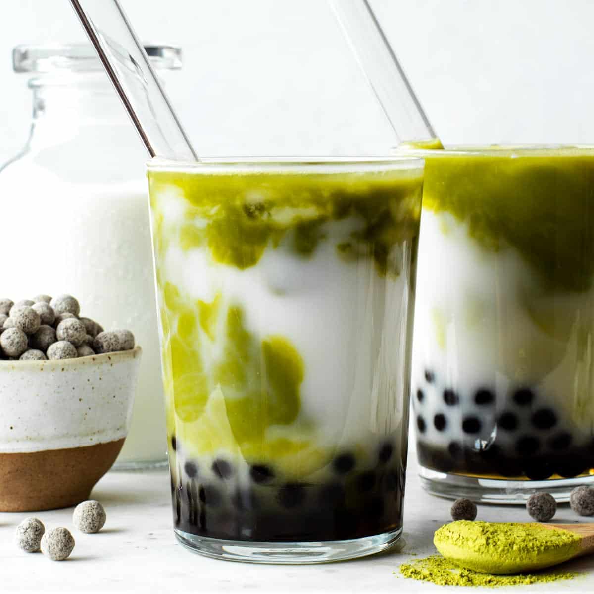 Matcha bubble tea in a glass with tapioca balls at the bottom.