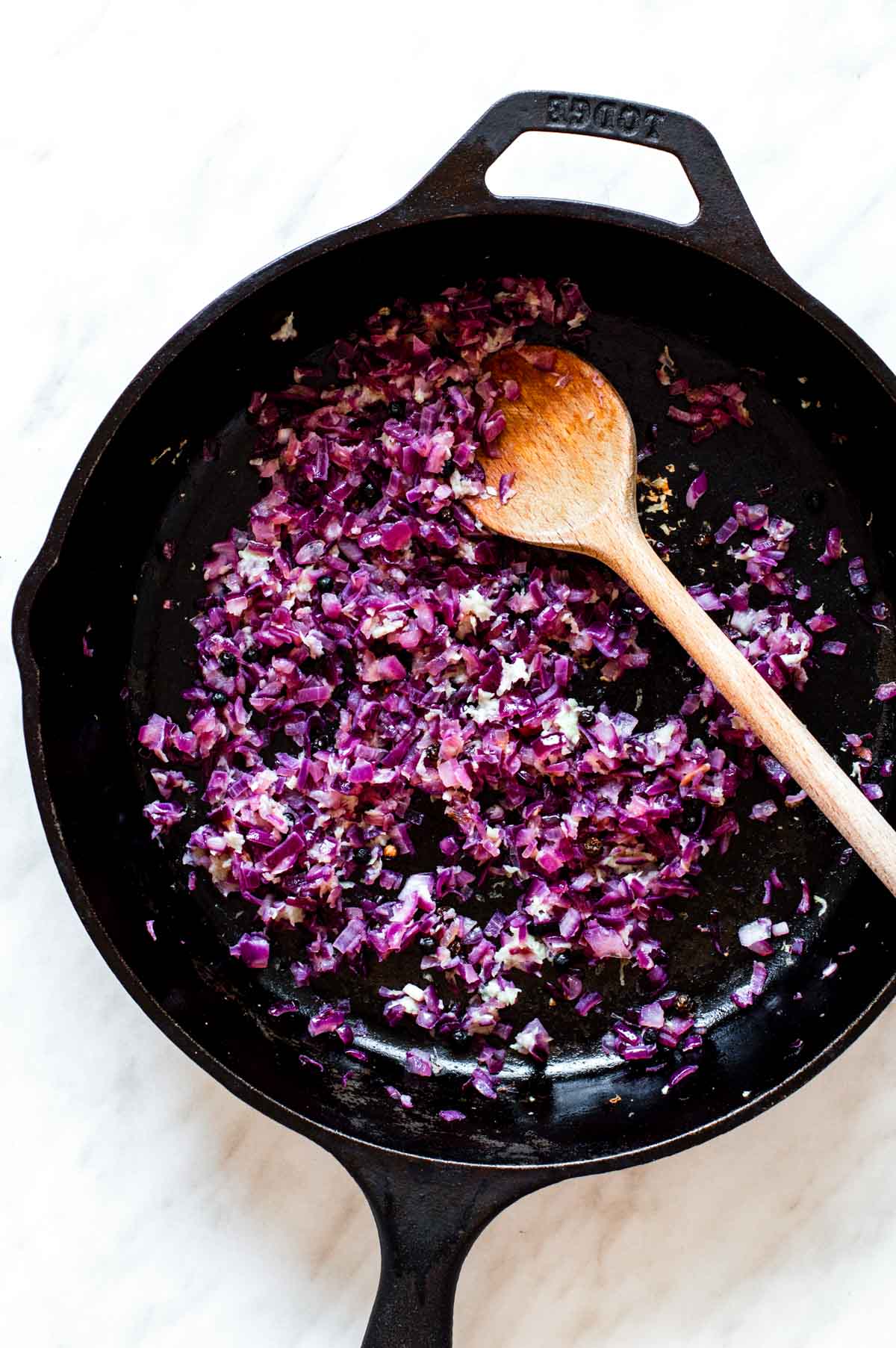 Sauteing red onion and minced garlic in a cast-iron skillet.
