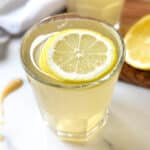 Apple cider vinegar and lemon juice in a glass, topped with a slice of lemon.