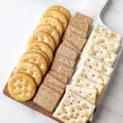 Various crackers lined up on a cheese board.