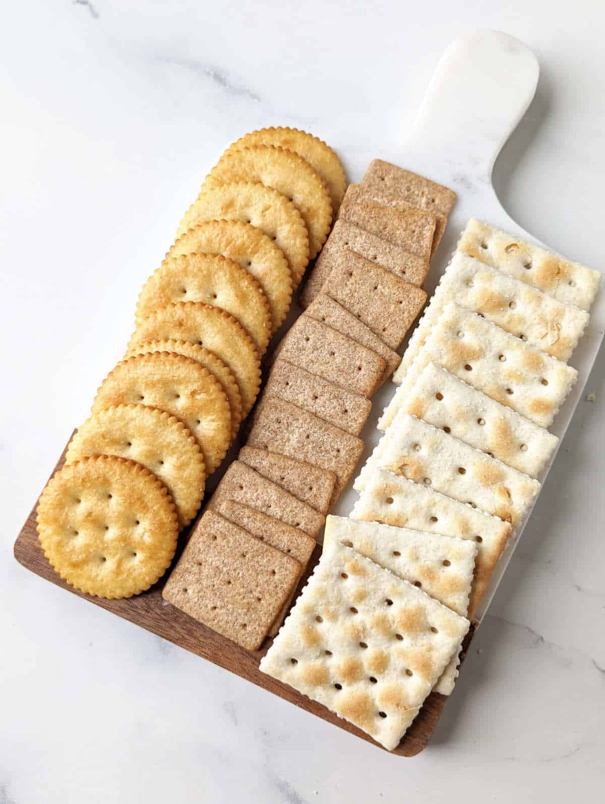 Various crackers lined up on a cheese board.
