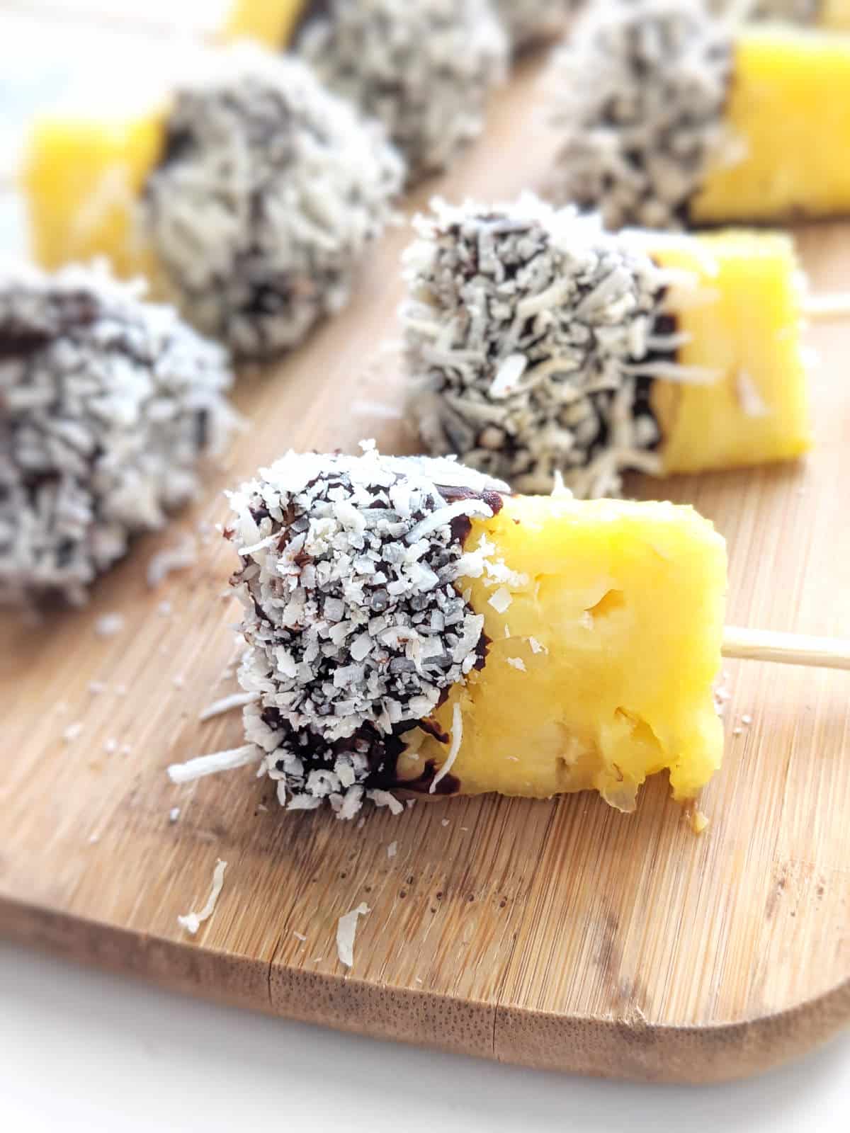 Chocolate covered pineapple on a wooden serving platter.