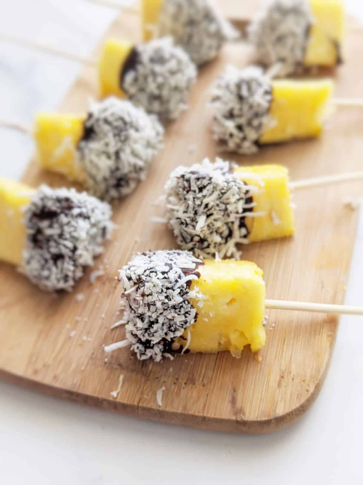 Chocolate covered pineapple bites on a serving platter.