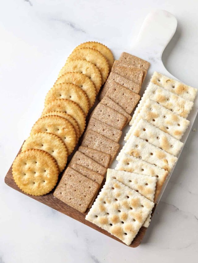 Various crackers lined up on a cheese board.