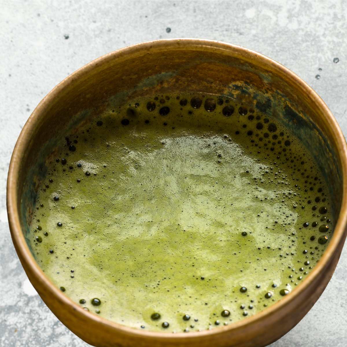 Frothy matcha tea in a small bowl.
