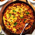 Large skillet filled with Mexican spaghetti, topped with melted dairy-free cheese and cilantro leaves.