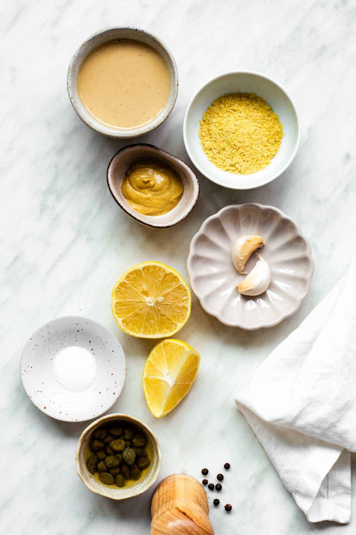 Gathered ingredients in various bowls for this tahini Caesar dressing.