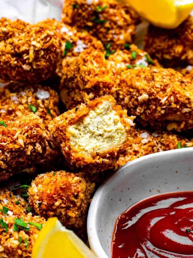 Tofu chicken bites served on a plate. One of the pieces has a bite takes off of it.