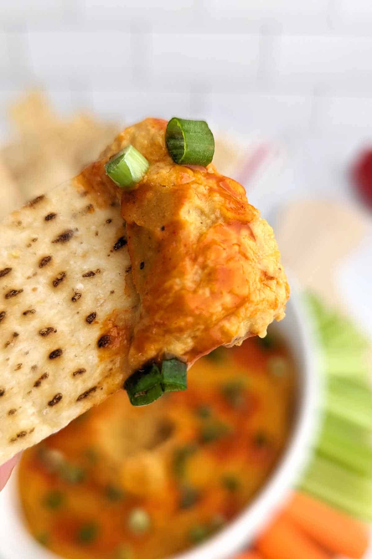 A tortilla chip with a scoop of this buffalo chickpea dip.