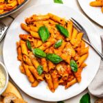 A plate of coconut milk pasta topped with fresh basil leaves.
