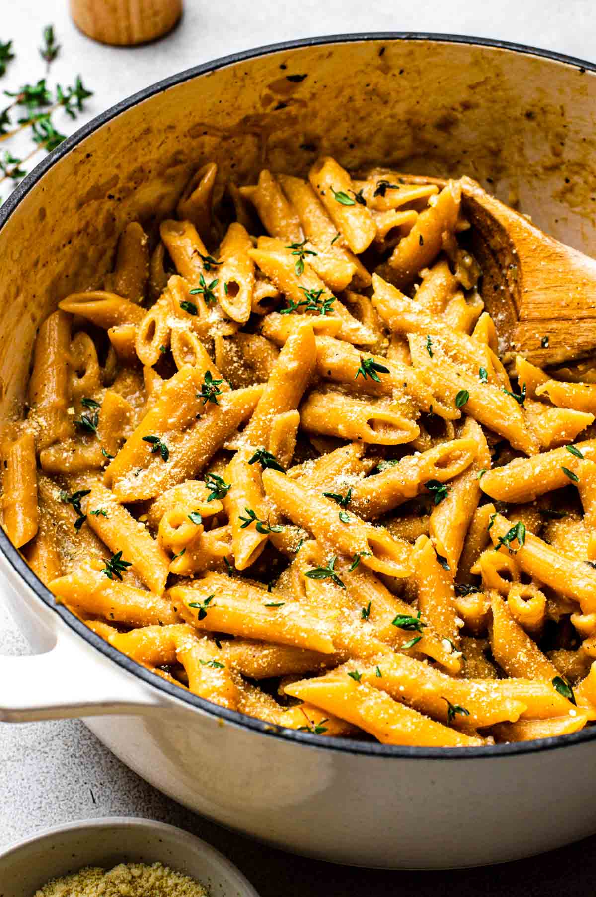 A Dutch oven of french onion pasta topped with thyme leaves.