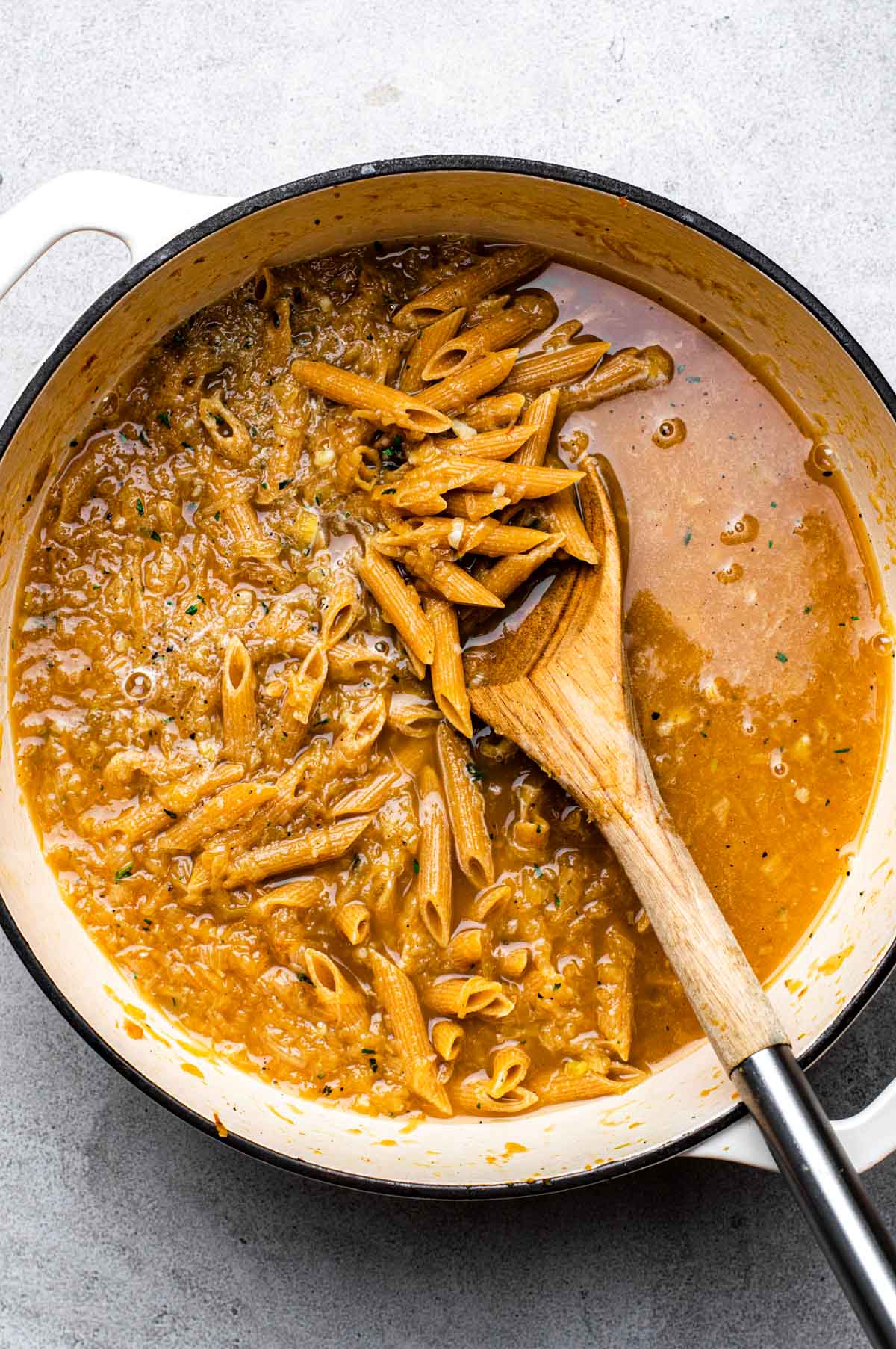 Pasta added to the Dutch oven pot and covered with broth.